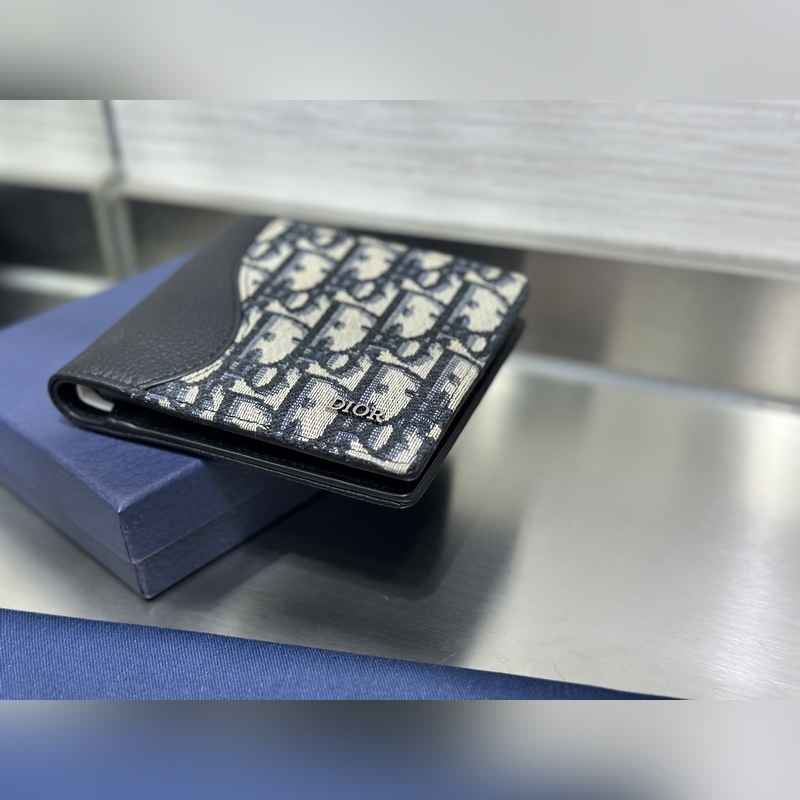 這款雙折錢包是一款小巧的配飾，精緻高雅。采用黑色粒面牛皮革精心制作，正面飾以 C