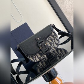 這款馬鞍手拿包附有肩帶，是二零二三春季男裝系列推出的新款單品，采用時尚的設計，彰